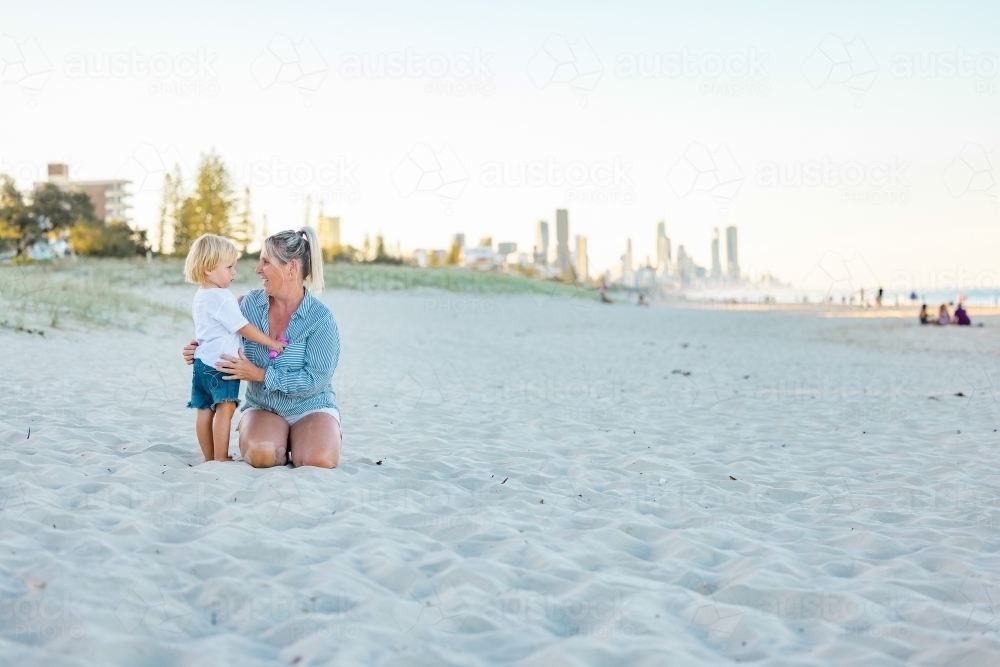 Mother and toddler son embracing on the sand of Gold Coast beach - Australian Stock Image