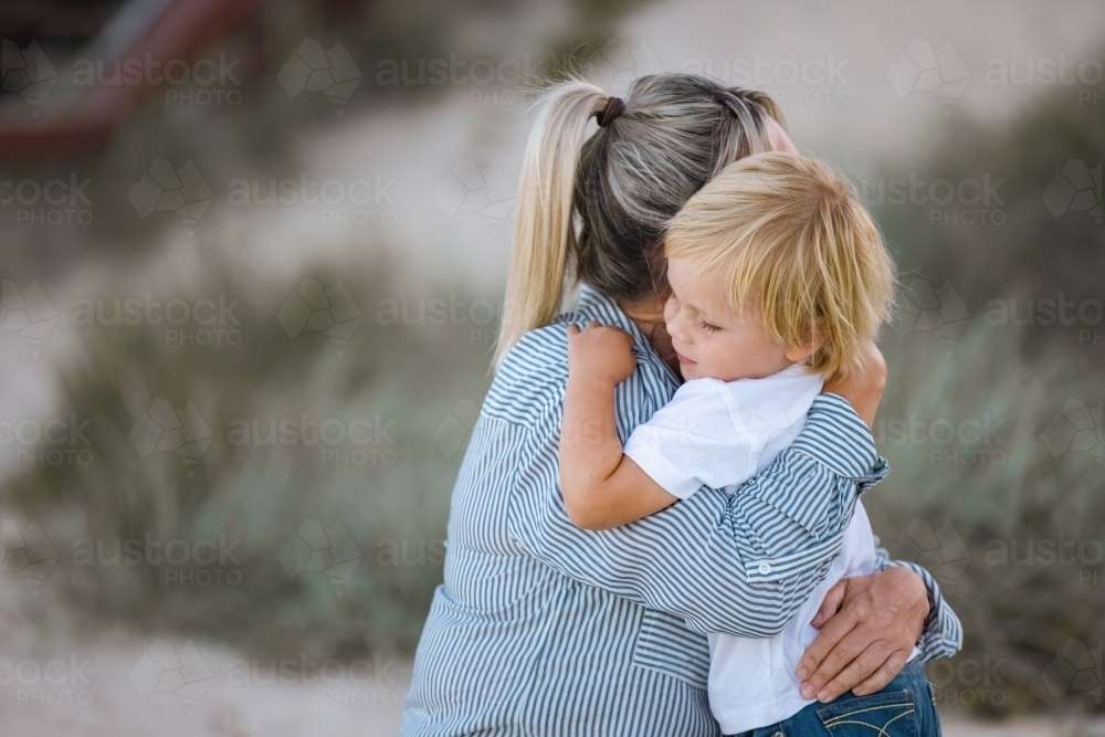 Mother and toddler son hugging on the beach - Australian Stock Image