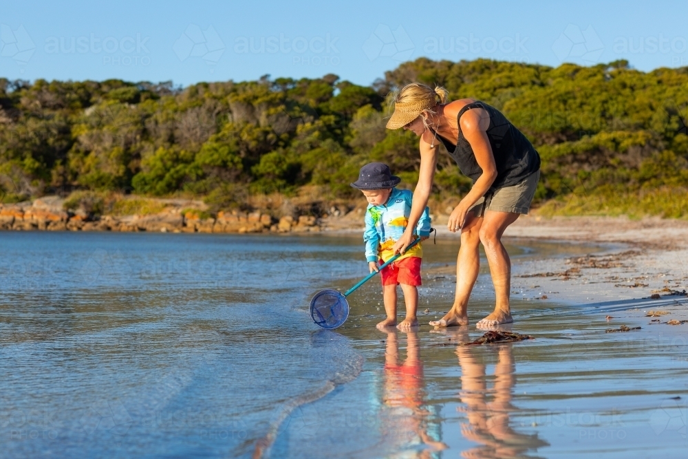 Mother and toddler with scoop net at the seashore - Australian Stock Image