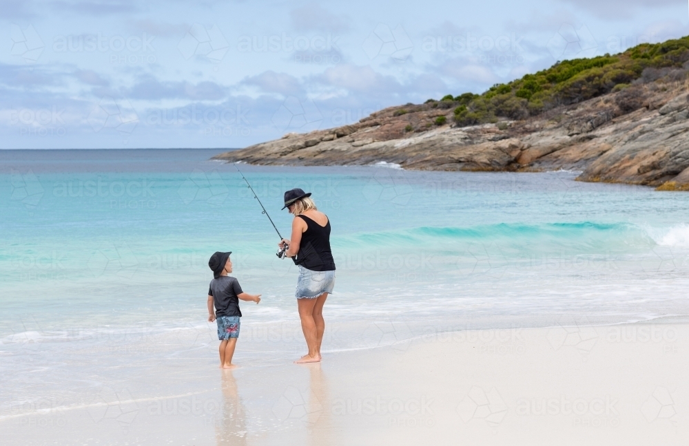 mother and young son fishing on white sand beach - Australian Stock Image
