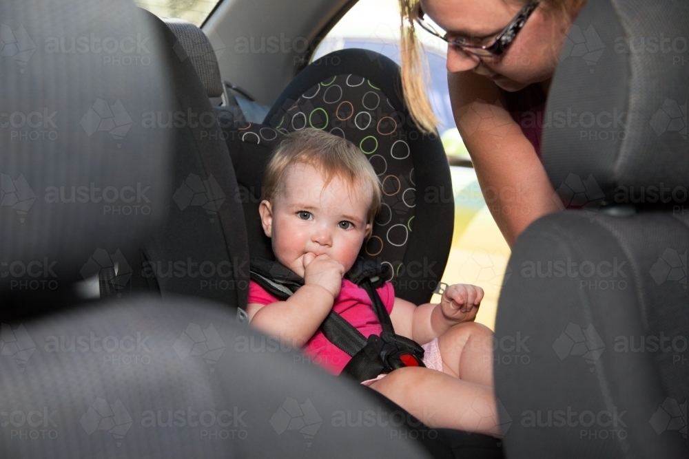 Mother attending to child in car seat - Australian Stock Image