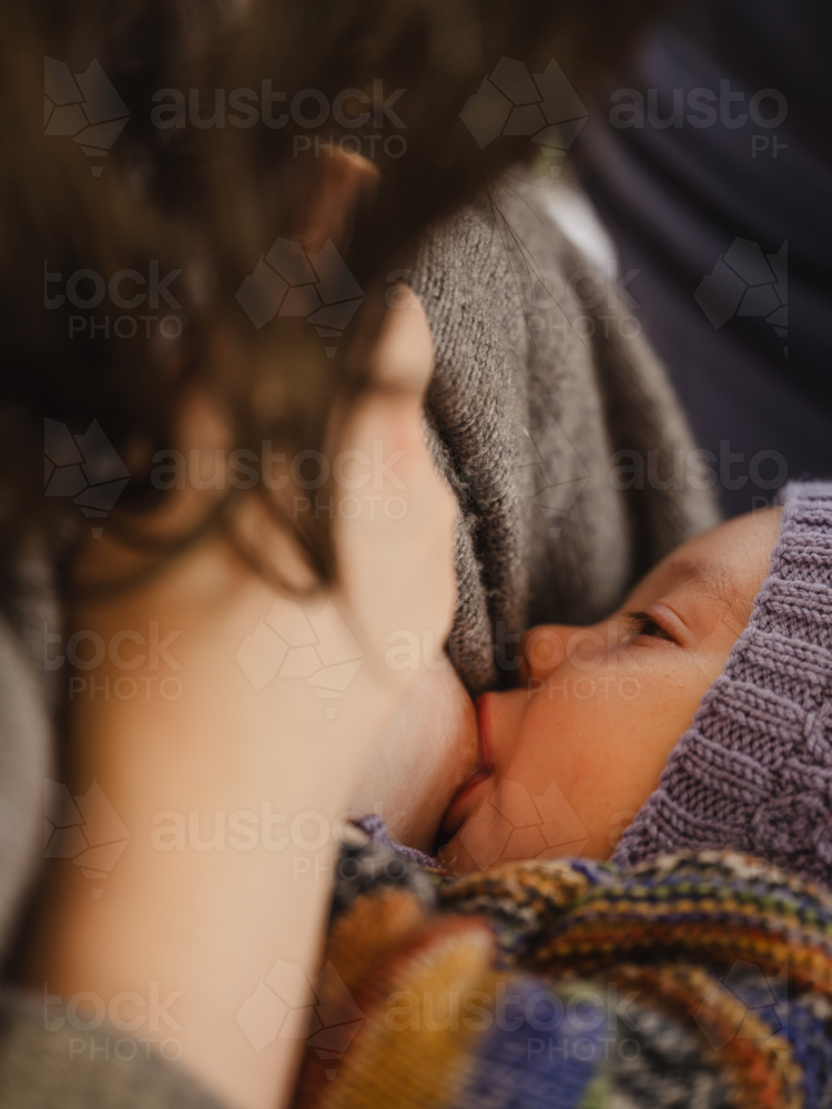 Mother breastfeeding baby wearing beanie - Australian Stock Image