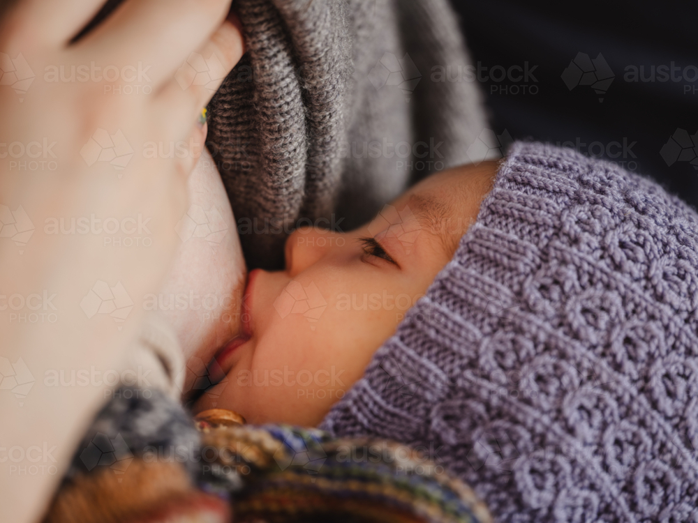 Mother breastfeeding baby wearing beanie - Australian Stock Image