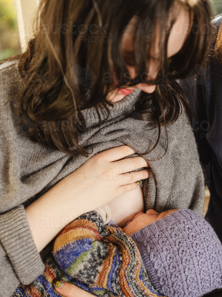 Mother breastfeeding baby wearing beanie - Australian Stock Image