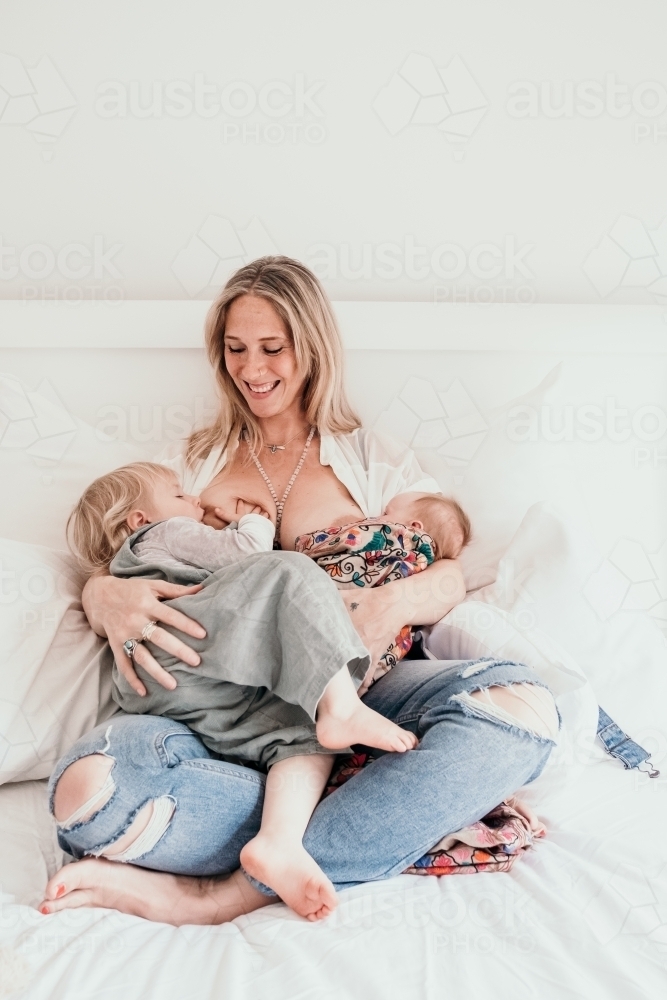 Mother breastfeeds two children. - Australian Stock Image