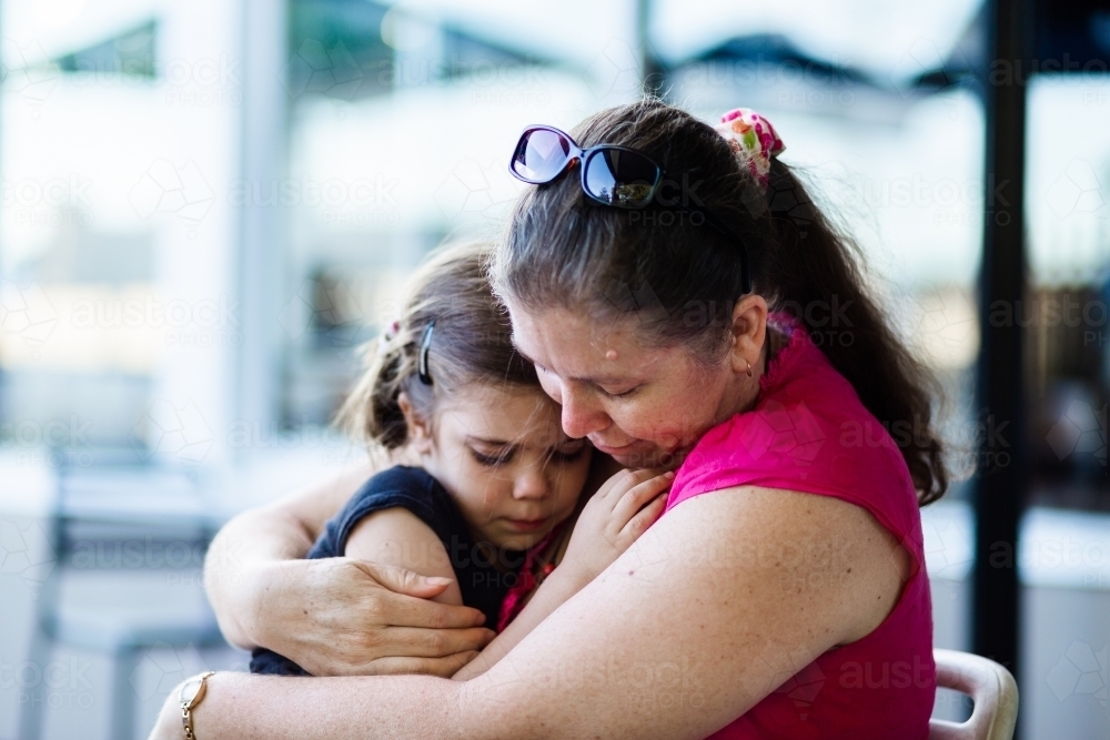 Mother comforts young daughter with close hug - Australian Stock Image