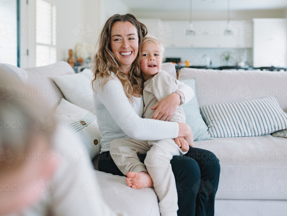 Mother cradles son on her lap in an embrace - Australian Stock Image