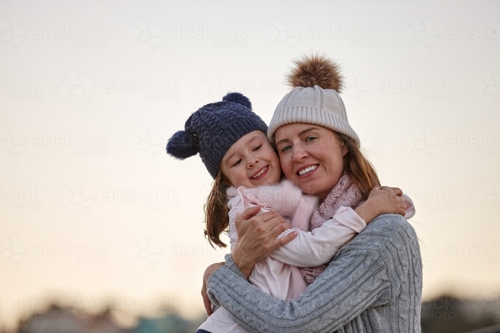 Mother cuddling daughter during winter - Australian Stock Image