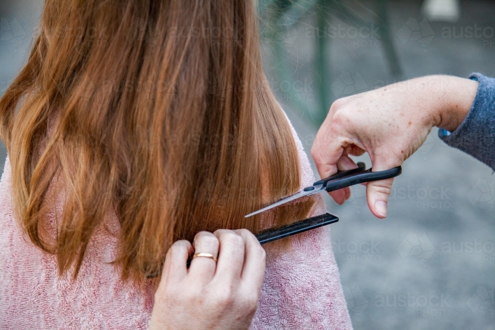 Mother cutting little girls hair at home - Australian Stock Image