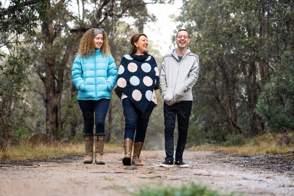 Mother, daughter, son smiling walking along bush track - Australian Stock Image