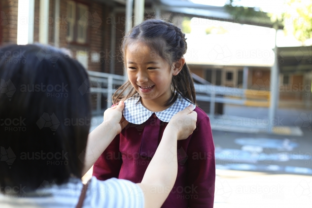 Mother fixing her daughters school uniform collar - Australian Stock Image