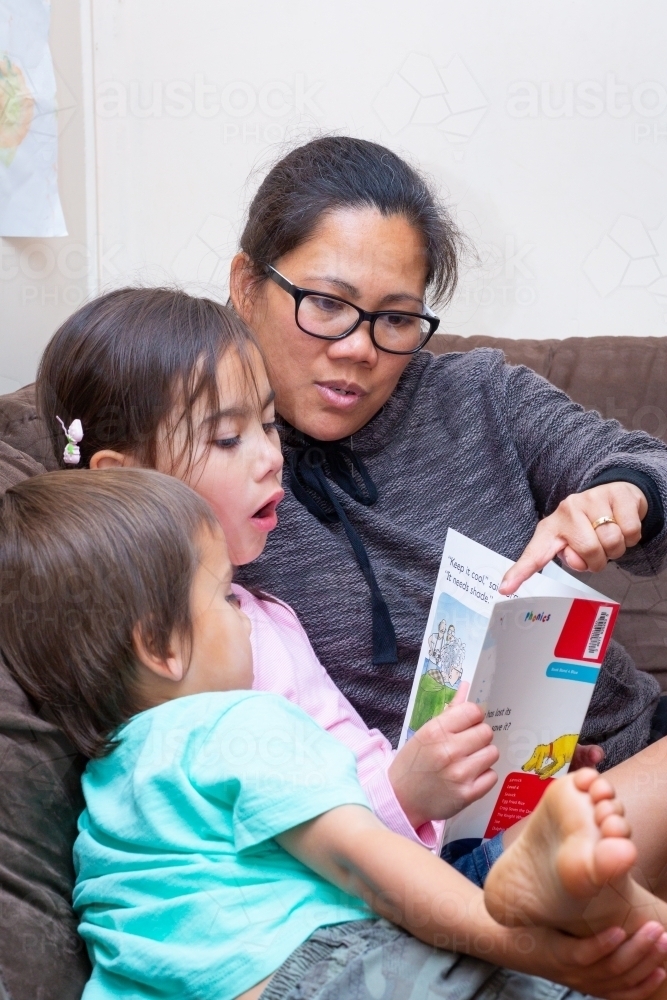 Mother helping child read a book - Australian Stock Image