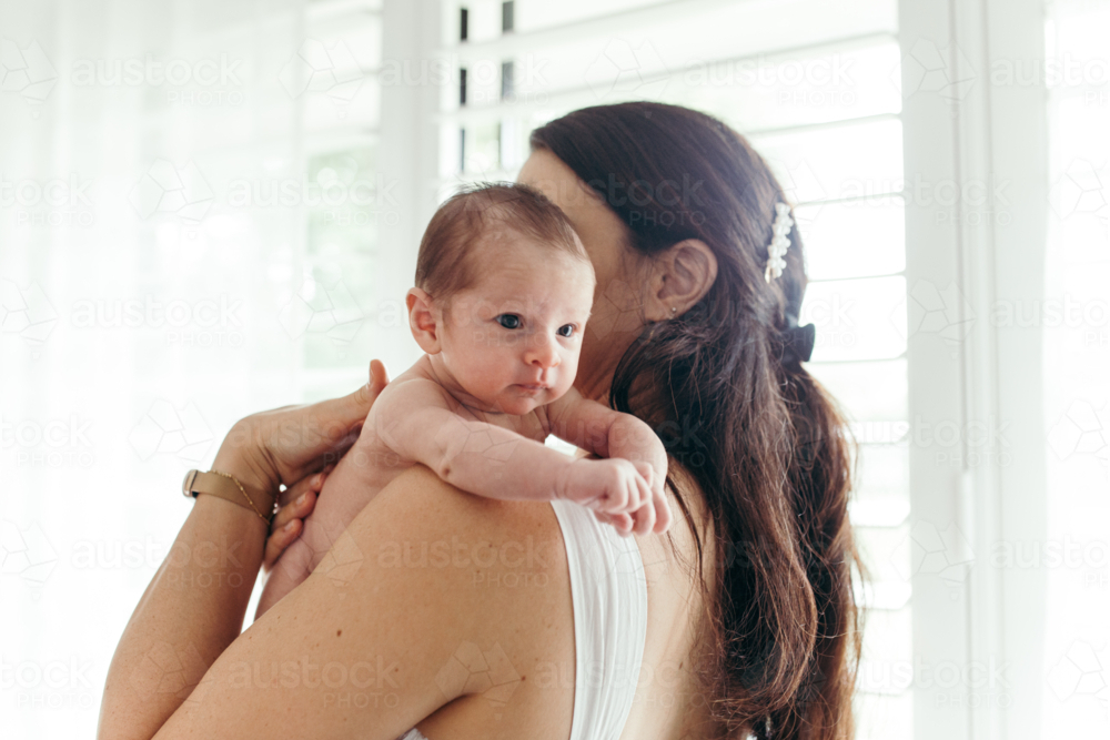 Mother holding a newborn baby girl upright on her shoulder - Australian Stock Image