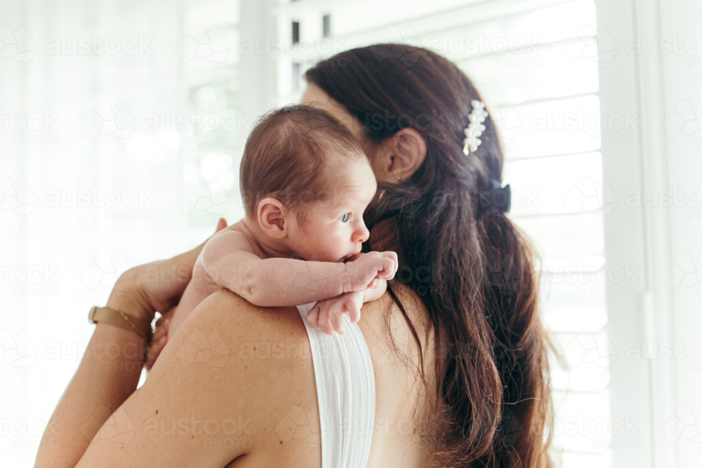 Mother holding a newborn baby girl upright on her shoulder - Australian Stock Image