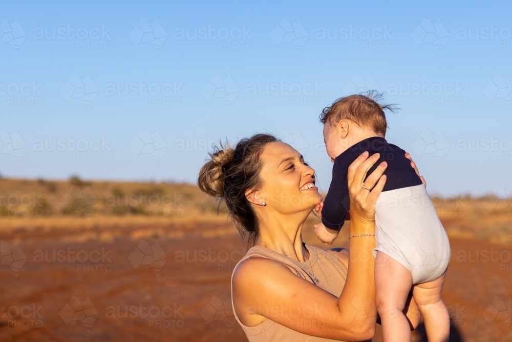 mother holding baby son up and looking at him lovingly - Australian Stock Image