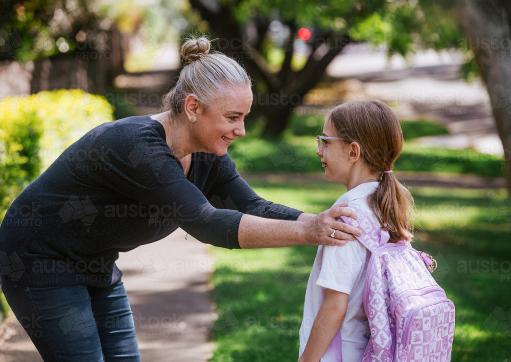 Mother holding daughter's shoulder while standing on the pathway - Australian Stock Image
