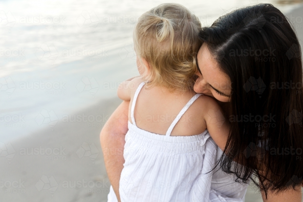 Mother holding her young daughter on the beach - Australian Stock Image
