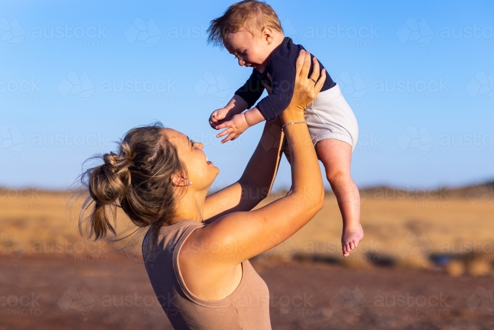 mother holding infant son up in the air - Australian Stock Image