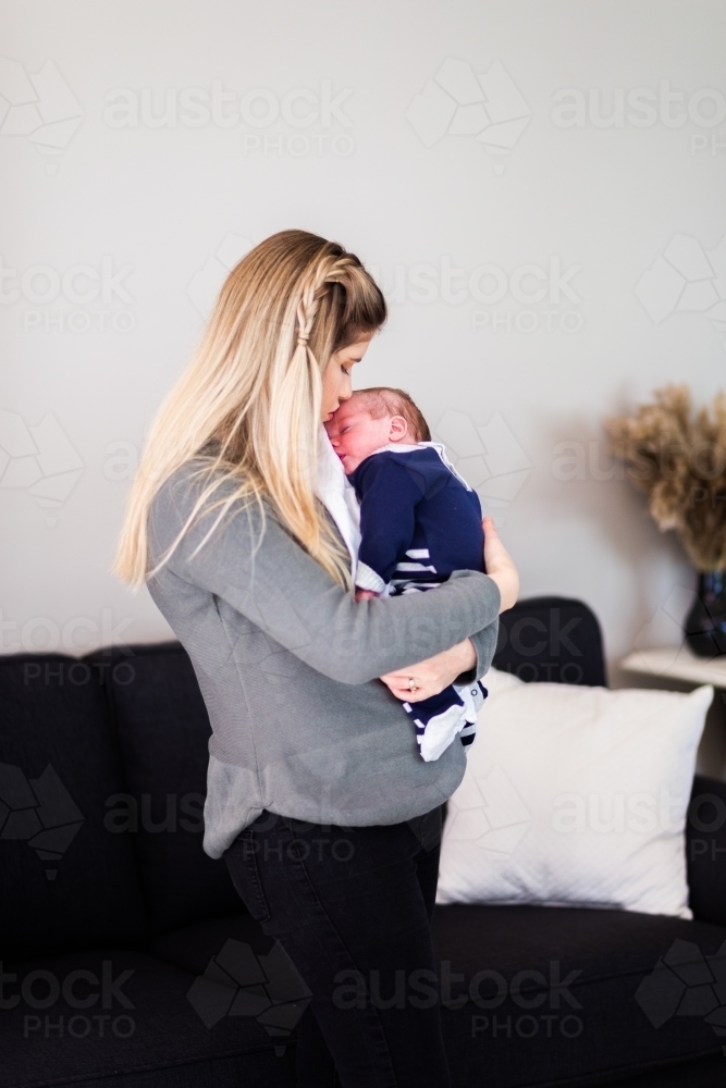 Mother holding newborn baby boy in arms cuddling - Australian Stock Image
