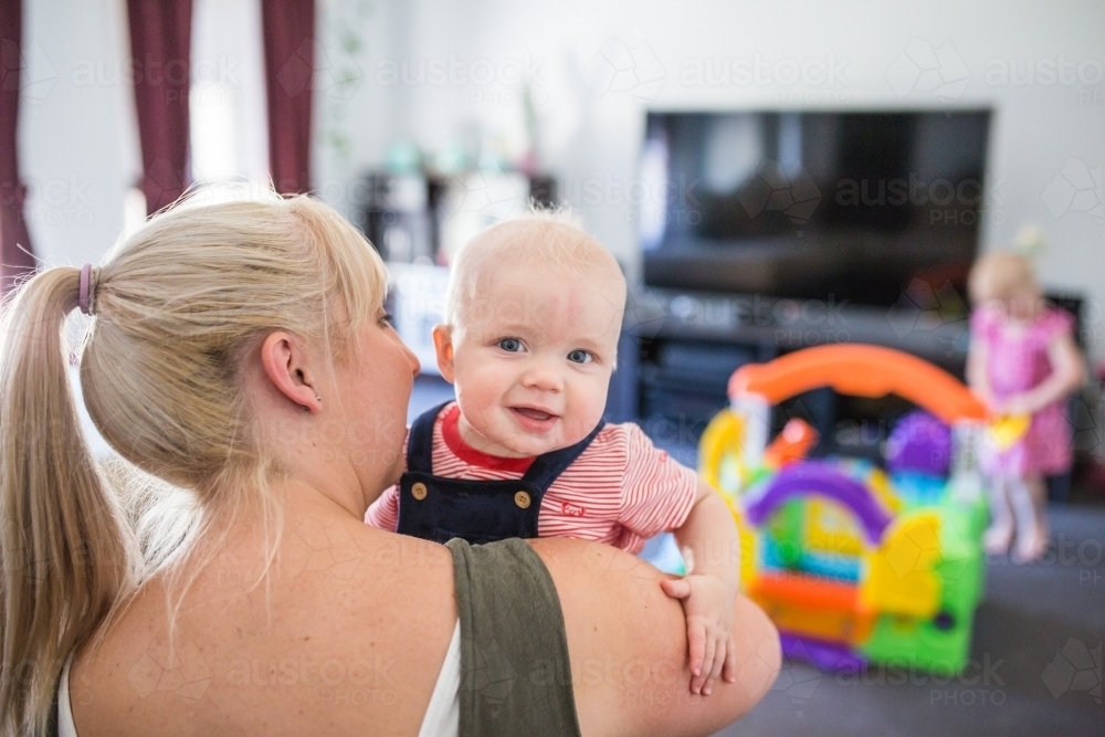 Mother holding son in arms with baby looking over shoulder - Australian Stock Image