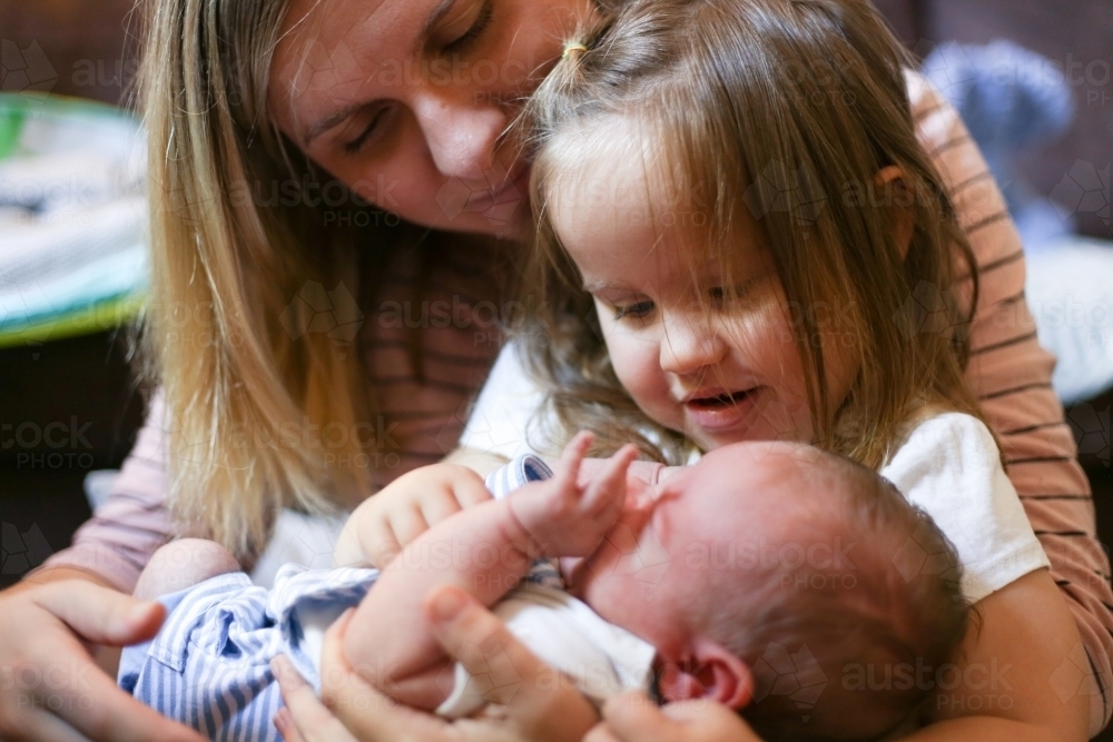 Mother holds her daughter and newborn son on her lap - Australian Stock Image