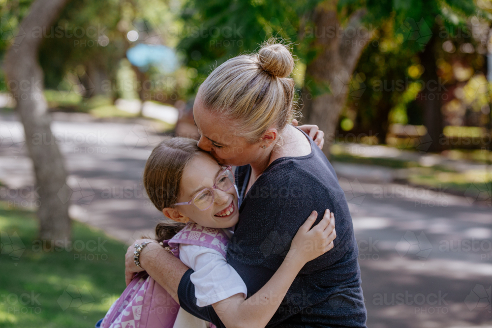 Mother hugging and kissing daughter on the head. - Australian Stock Image