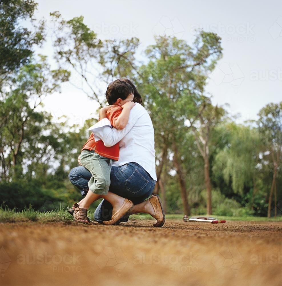 Mother hugging child on bush track after a fall - Australian Stock Image