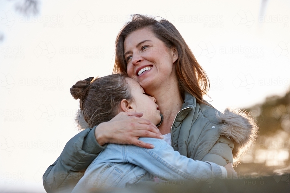 Mother hugging her daughter outdoors - Australian Stock Image