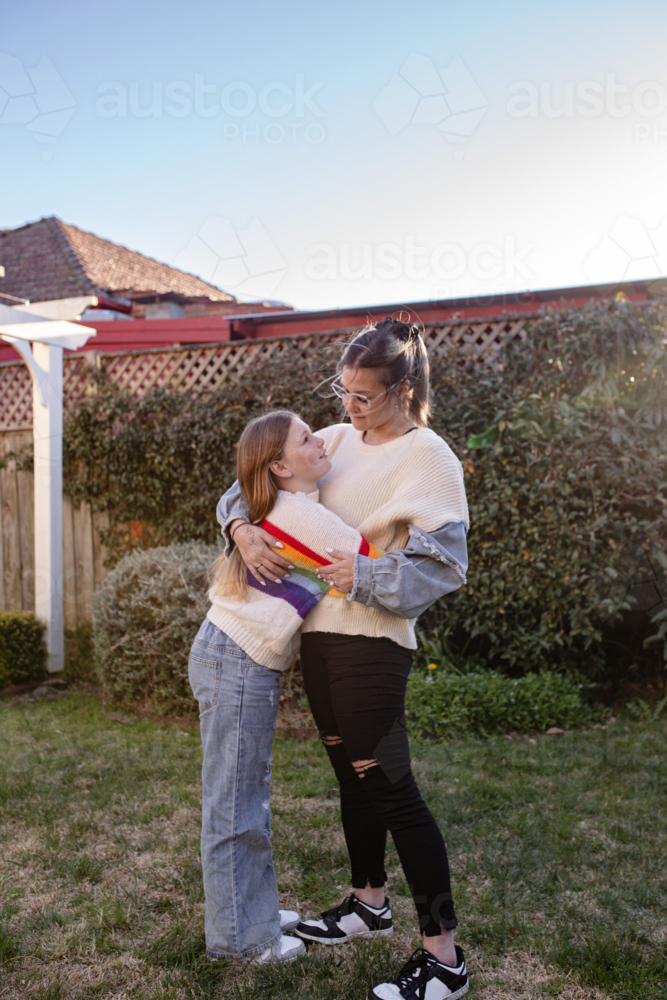 Mother hugging preteen daughter in the garden - Australian Stock Image