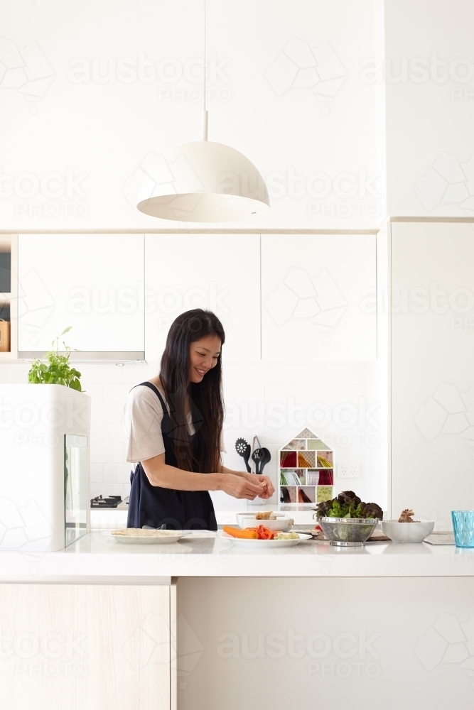 Mother in kitchen preparing meal - Australian Stock Image