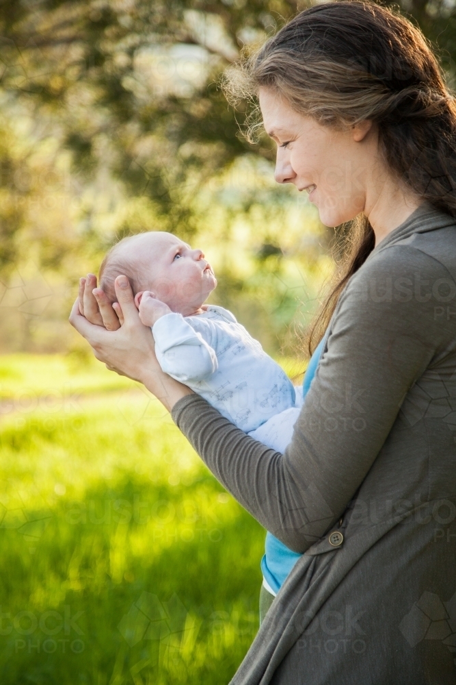 Mother interacting with newborn baby boy outside - Australian Stock Image