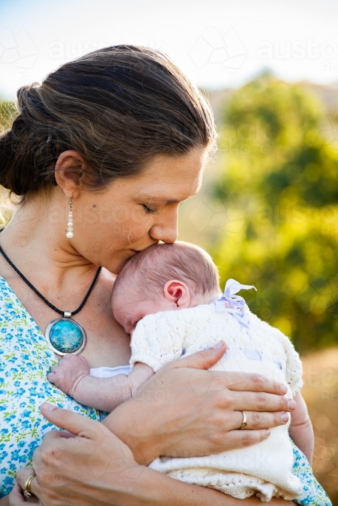 Mother kissing newborn baby - Australian Stock Image