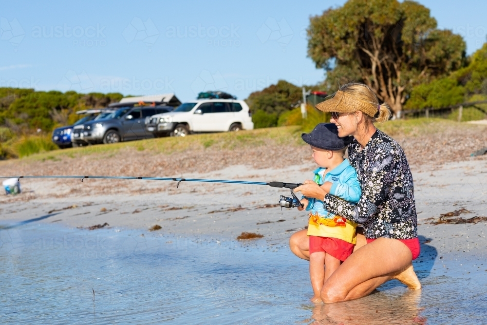 Mother kneeling to help her son fishing - Australian Stock Image