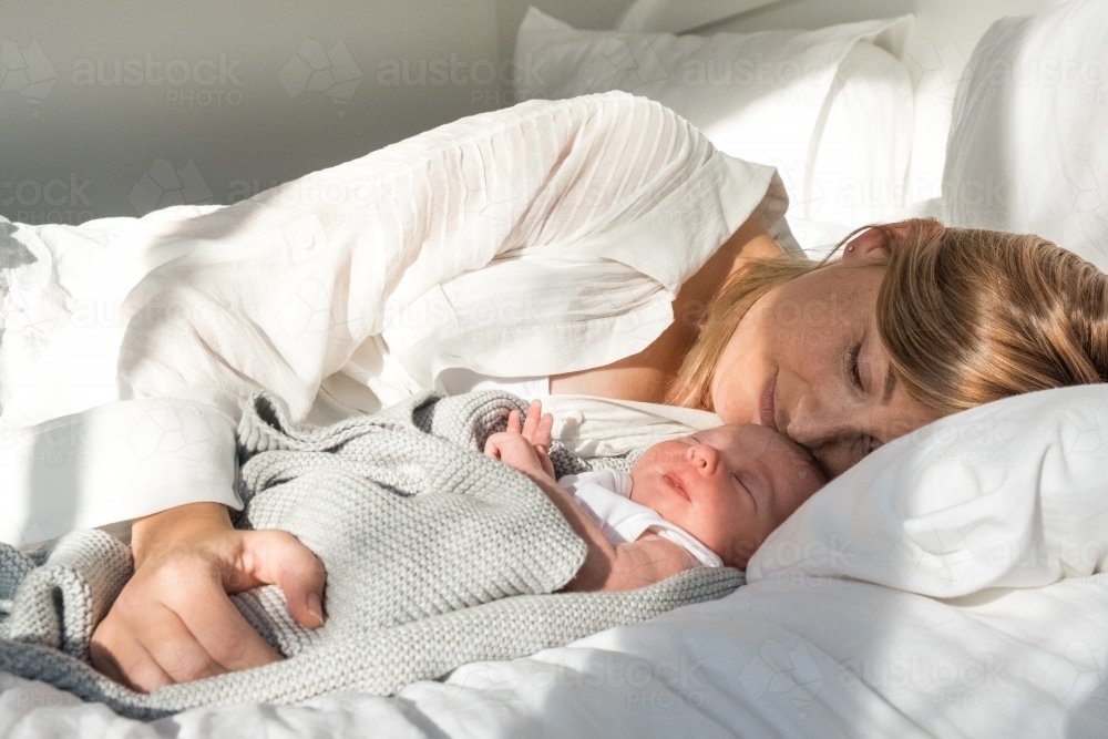 Mother lies next to newborn baby. - Australian Stock Image