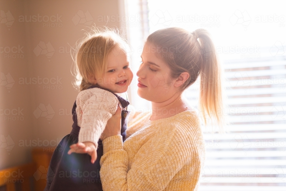 Mother lifting happy toddler up - Australian Stock Image