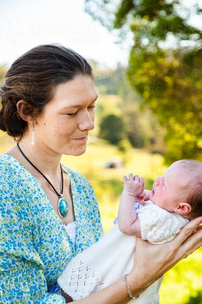 Mother looking at her newborn daughter smiling outside - Australian Stock Image