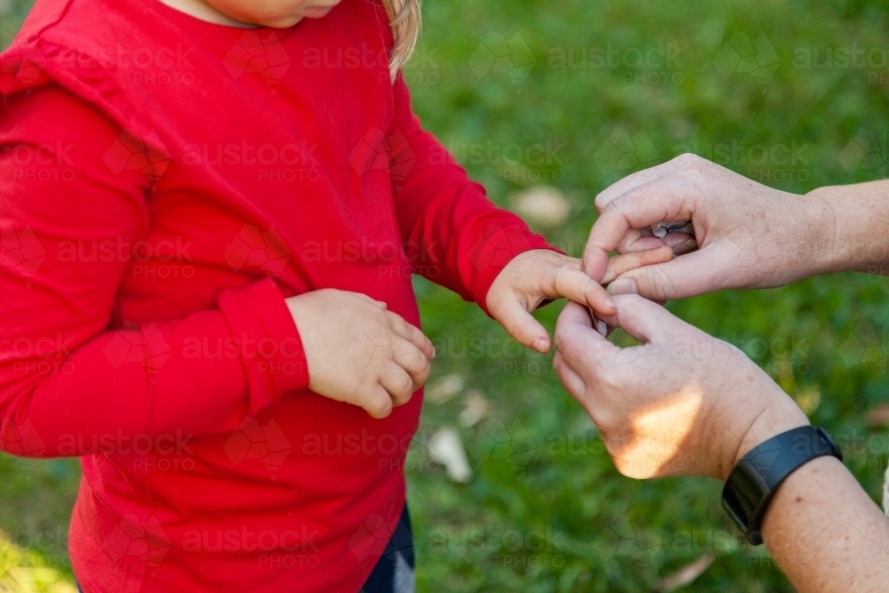 Mother putting band aid on child's cut finger - Australian Stock Image