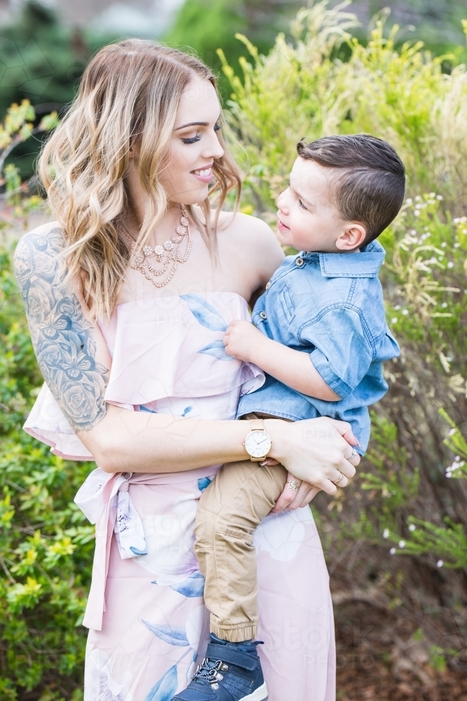 Mother smiling down at mixed race aboriginal caucasian son in arms - Australian Stock Image