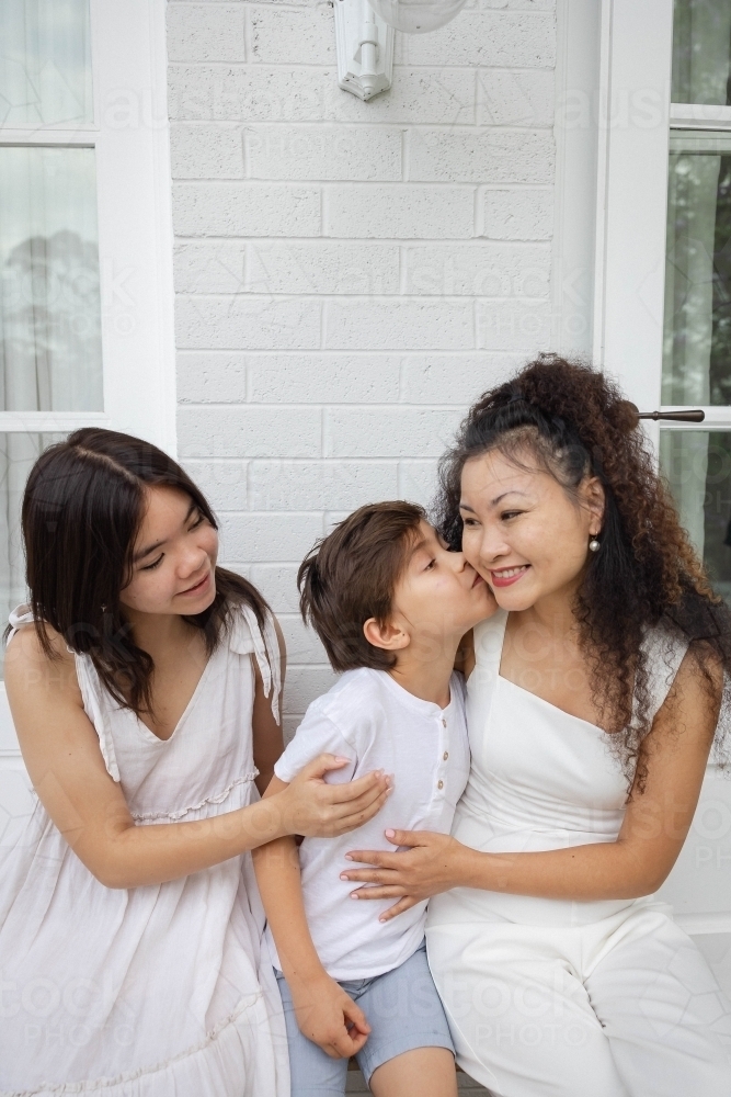 Mother, son and daughter wearing white sitting together - Australian Stock Image