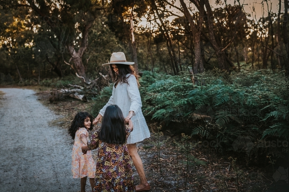 Mother with two children at the park holding hands - Australian Stock Image