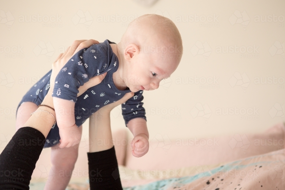 Mothers arms holding up baby boy - Australian Stock Image