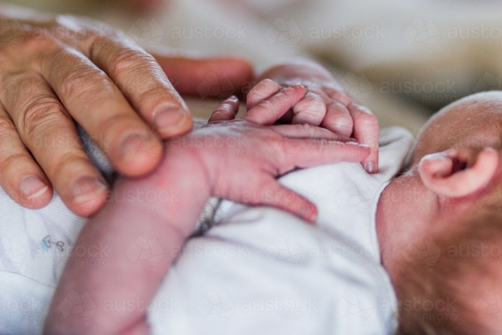 Mothers hand on newborn baby - Australian Stock Image