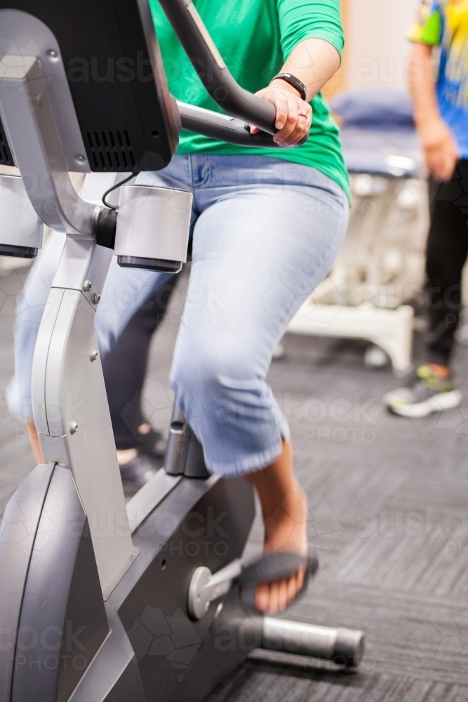 motion blur of woman pedalling exercise bike - Australian Stock Image
