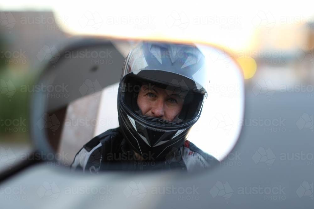 motorbike rider looking in rear view mirror - Australian Stock Image
