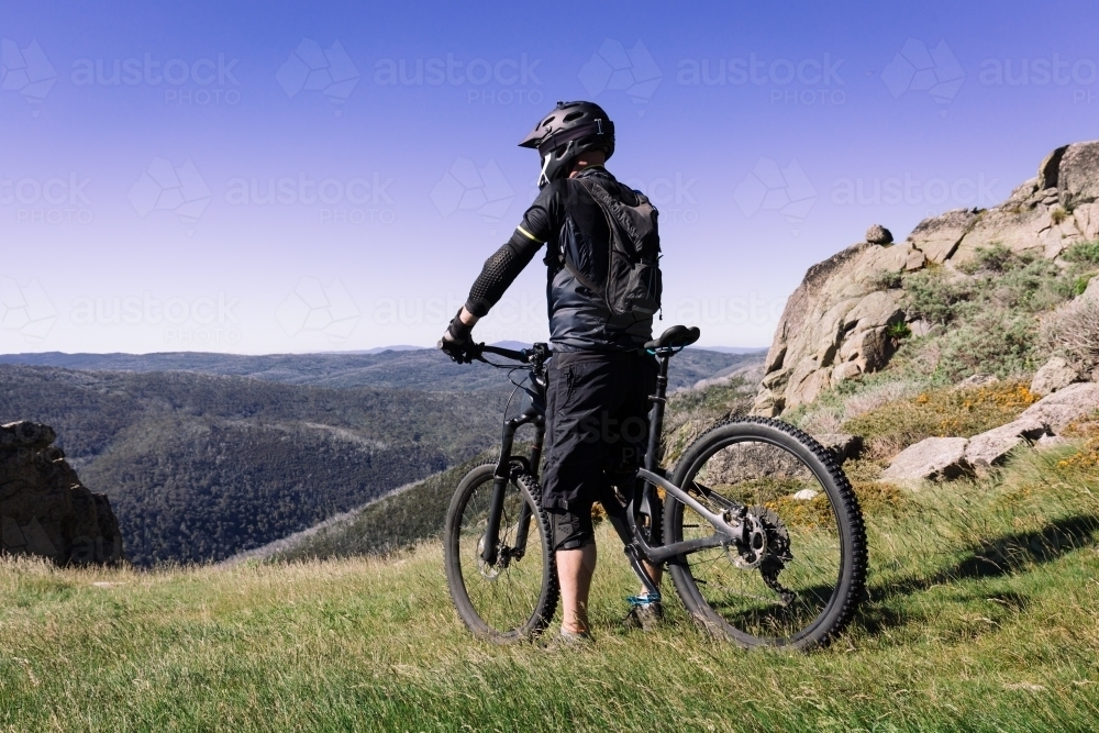 Mountain biker contemplating riding down Mount Kosciuscko - Australian Stock Image