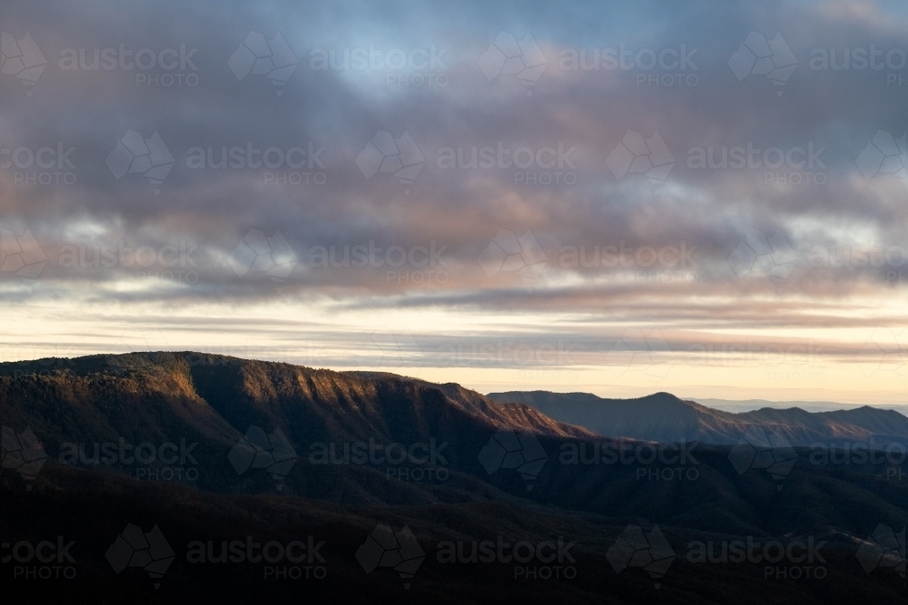 Mountain ranges with morning light and cloudy sky - Australian Stock Image