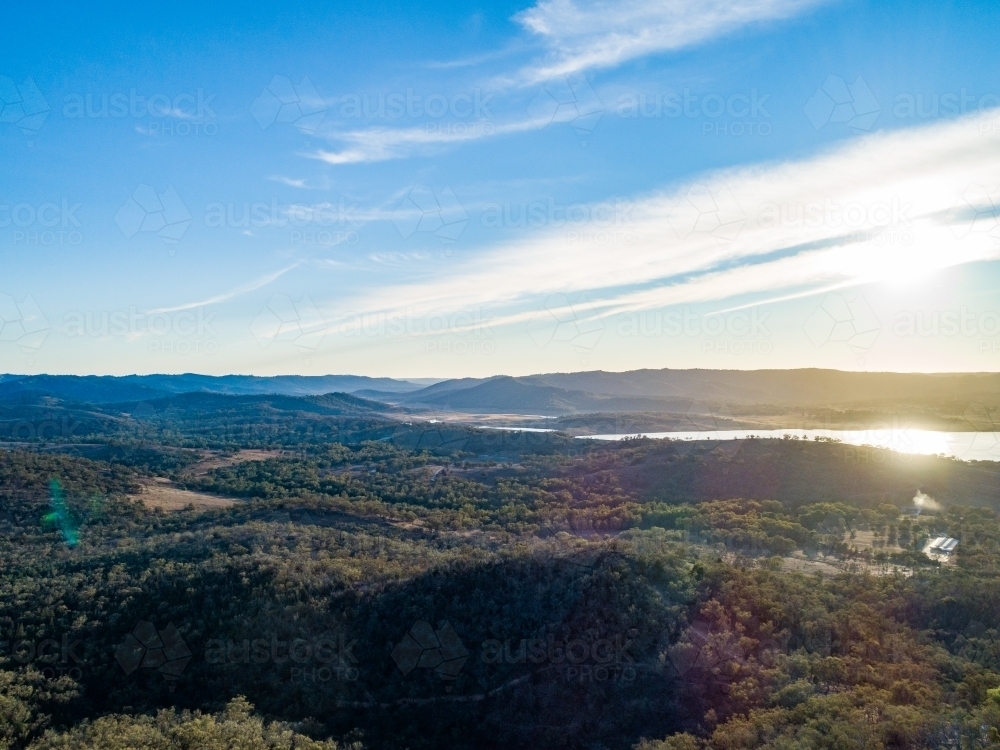 Mountains covered in dry gum trees with sunlight off water in Lake Burrendong Mumbil NSW - Australian Stock Image
