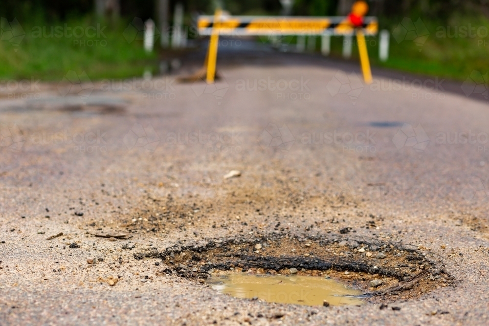 Image of Muddy pot hole in gravel road closed because of flooding