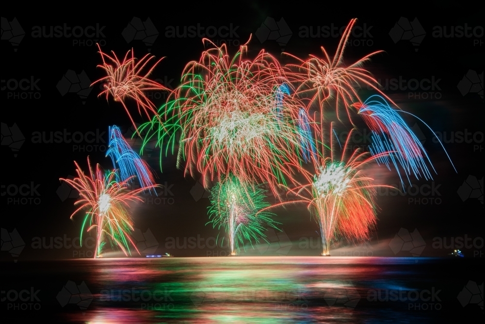 Exploding Rainbow Firework Image of Multi coloured fireworks exploding over an ocean in the night ...