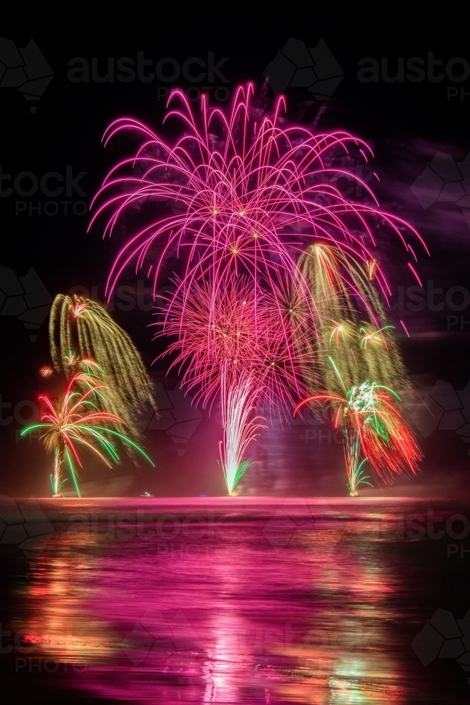 Image of Multi coloured fireworks exploding over an ocean in the night ...